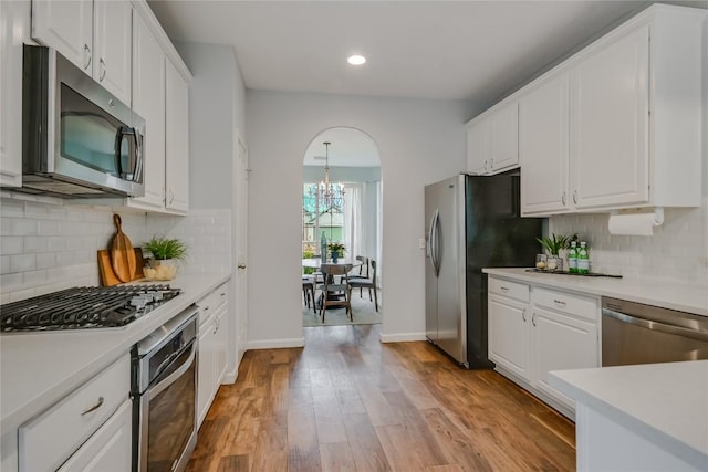 kitchen with white cabinetry, appliances with stainless steel finishes, light countertops, and wood finished floors