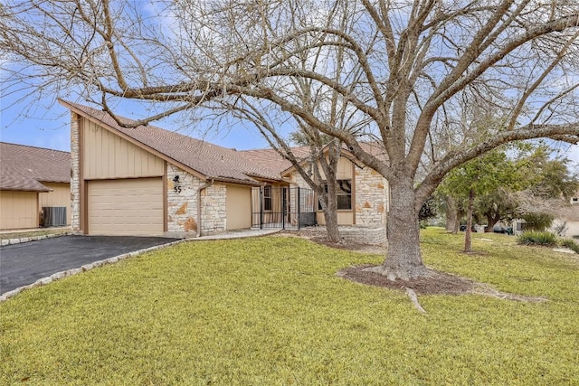 view of front facade with an attached garage, stone siding, driveway, and central AC unit