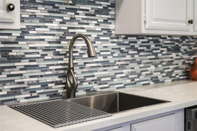 interior details with white cabinetry, decorative backsplash, and light countertops