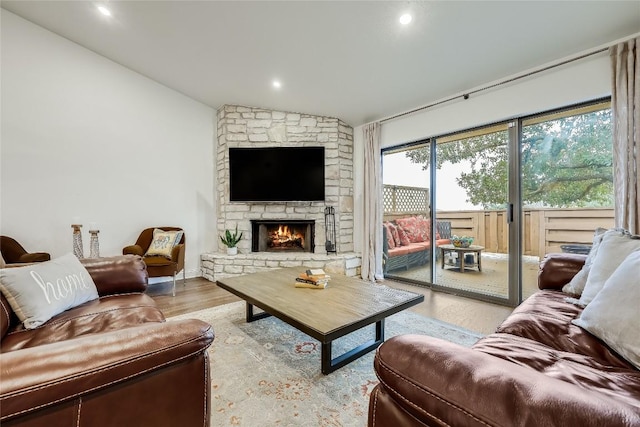living area with lofted ceiling, a fireplace, and wood finished floors