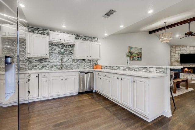 kitchen featuring dark wood-style floors, vaulted ceiling with beams, light countertops, stainless steel dishwasher, and a peninsula
