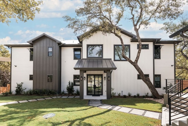 modern farmhouse featuring board and batten siding, a standing seam roof, metal roof, and a front lawn