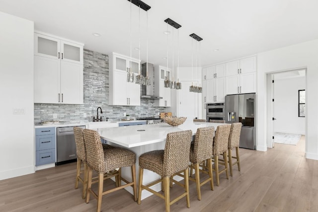 1105 Oak Hurst Rd, Austin, TX 78734 - kitchen featuring stainless steel appliances, wall chimney range hood, a breakfast bar, a kitchen island, and white cabinets
