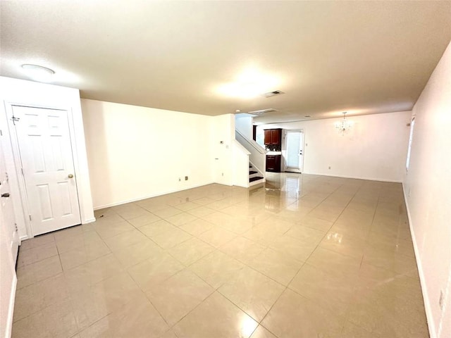 spare room featuring light tile patterned flooring, a notable chandelier, stairway, and baseboards