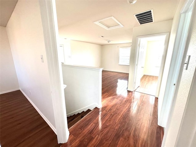 corridor featuring dark wood finished floors, visible vents, attic access, an upstairs landing, and baseboards