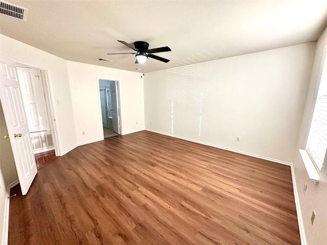 interior space with baseboards, ensuite bath, visible vents, and wood finished floors