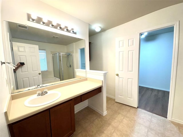 full bathroom with a shower stall, visible vents, baseboards, and vanity