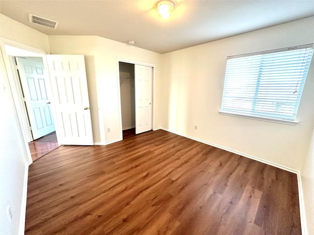 unfurnished bedroom featuring a closet, wood finished floors, visible vents, and baseboards