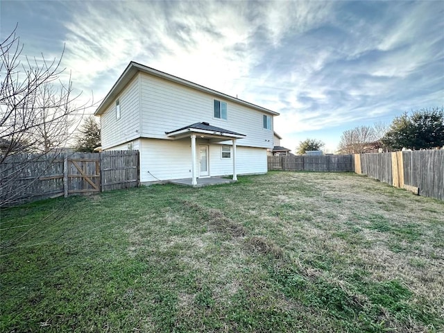 rear view of house with a patio area, a fenced backyard, and a lawn