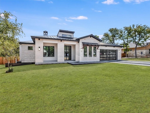 rear view of house featuring metal roof, a garage, a yard, driveway, and a standing seam roof