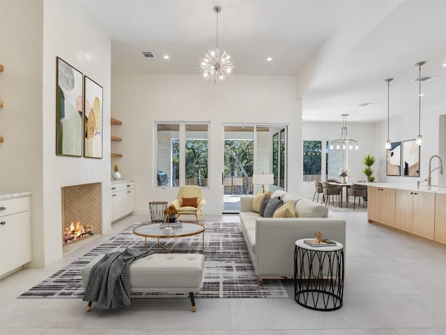 living room featuring a chandelier, a tiled fireplace, visible vents, and recessed lighting