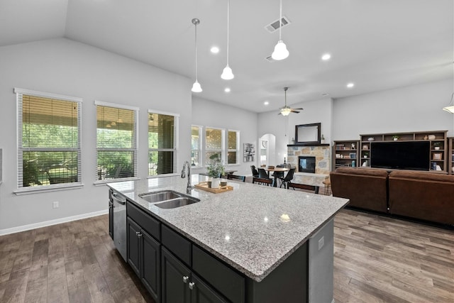 kitchen featuring a stone fireplace, dark wood-style flooring, a sink, and visible vents