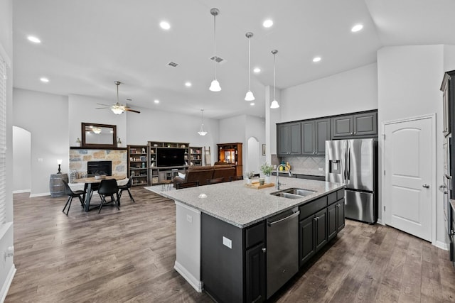 kitchen featuring arched walkways, a stone fireplace, stainless steel appliances, a sink, and visible vents