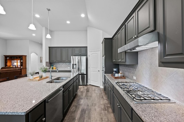 kitchen featuring arched walkways, under cabinet range hood, stainless steel appliances, a sink, and dark wood-style floors