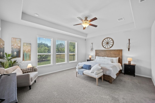 carpeted bedroom with a tray ceiling, visible vents, and baseboards