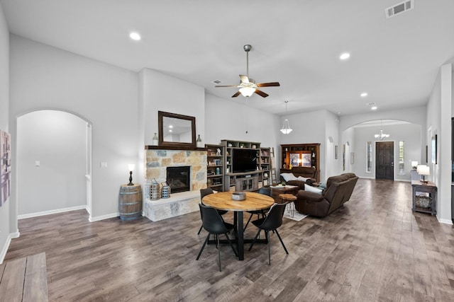 living area with visible vents, a fireplace, arched walkways, and wood finished floors