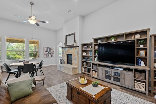 living room featuring high vaulted ceiling, a fireplace, wood finished floors, visible vents, and a ceiling fan