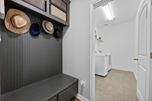 mudroom with light tile patterned floors, visible vents, baseboards, and washing machine and clothes dryer