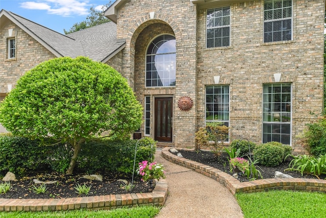 view of exterior entry with a shingled roof