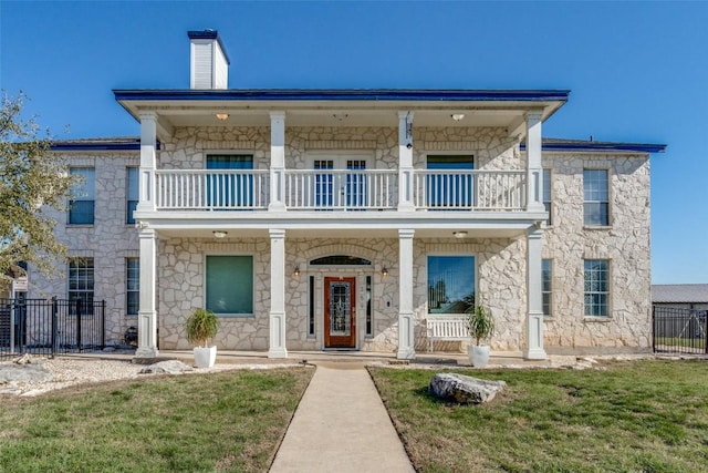 view of front of property with a porch, a chimney, fence, and a balcony