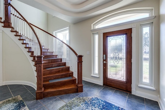 entrance foyer with a healthy amount of sunlight, dark tile patterned floors, and baseboards