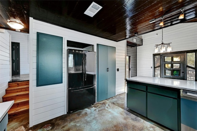 kitchen with concrete flooring, wooden ceiling, green cabinets, and freestanding refrigerator