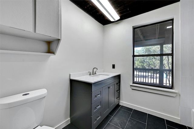 bathroom with tile patterned flooring, baseboards, vanity, and toilet