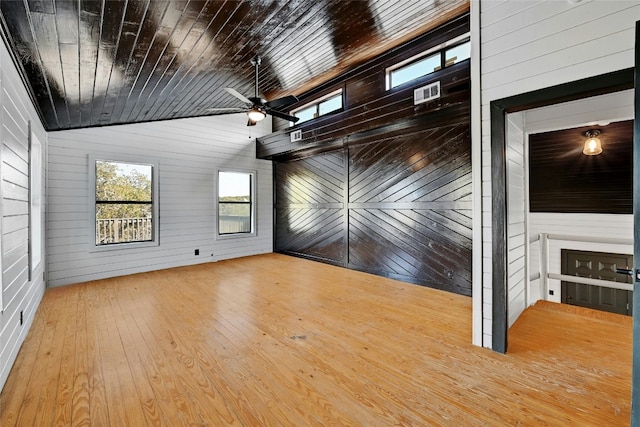 unfurnished room featuring lofted ceiling, wood-type flooring, wood ceiling, ceiling fan, and wood walls