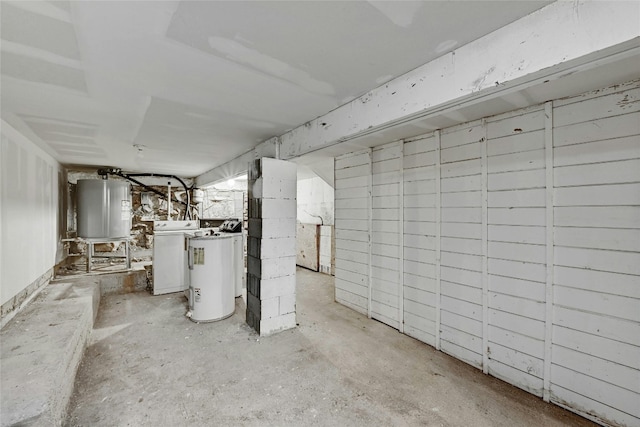 unfinished basement with water heater and washer / clothes dryer