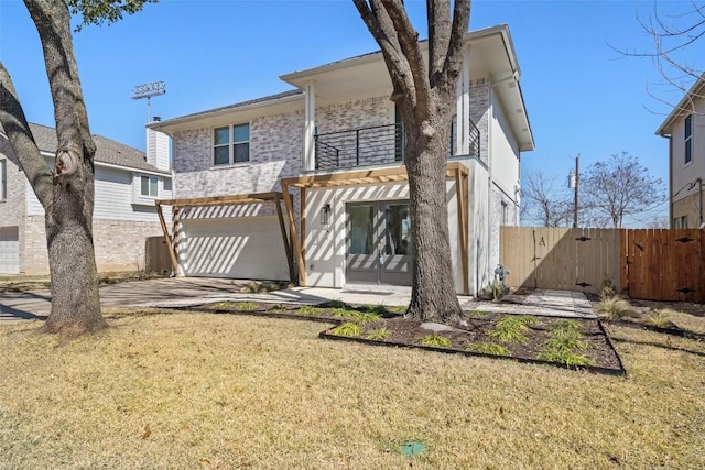 back of house with fence, an attached garage, a balcony, a gate, and a patio area