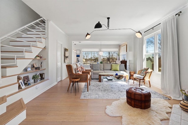 living room featuring stairs, ornamental molding, a wealth of natural light, and light wood finished floors