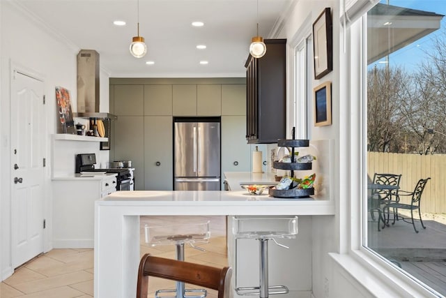 kitchen featuring light countertops, wall chimney exhaust hood, crown molding, and appliances with stainless steel finishes