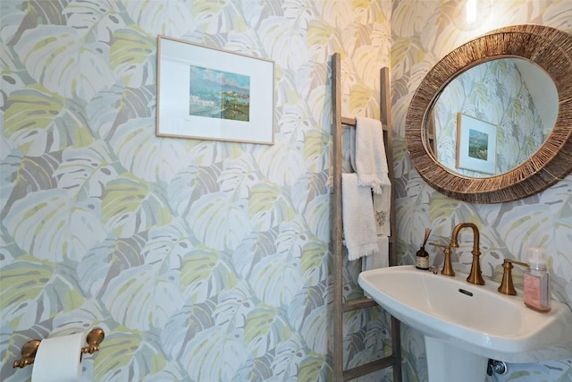 half bath with wallpapered walls and a sink
