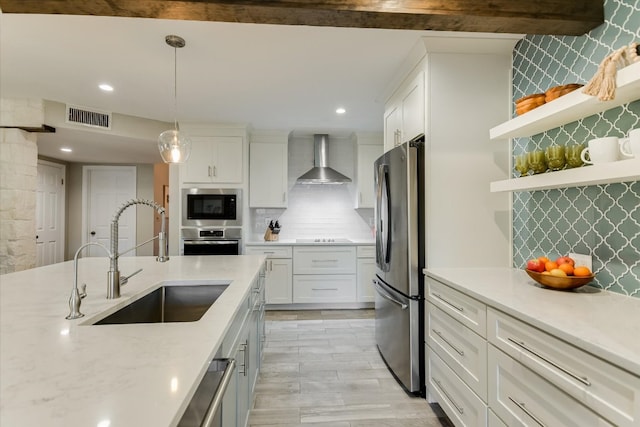 kitchen featuring stainless steel appliances, visible vents, white cabinets, a sink, and wall chimney exhaust hood