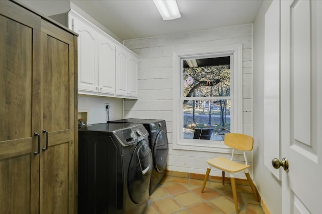laundry room with washer and dryer, cabinet space, and wood walls