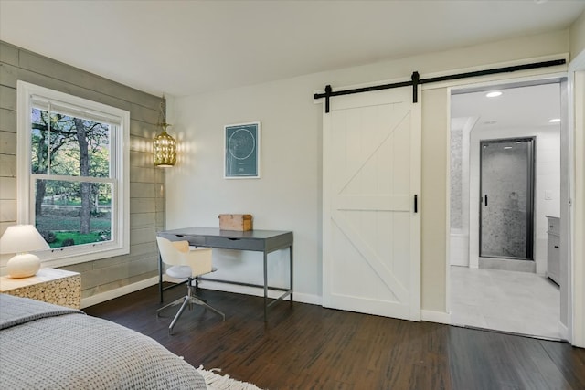 bedroom featuring a barn door, dark wood finished floors, and baseboards