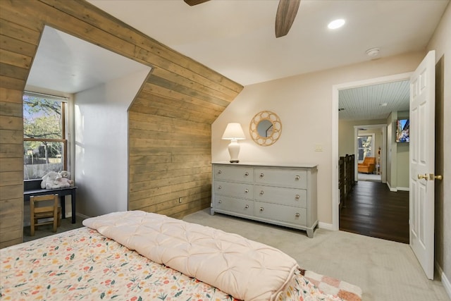 bedroom featuring lofted ceiling, carpet flooring, ceiling fan, wooden walls, and baseboards