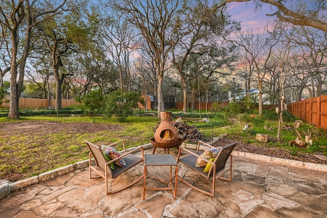 patio terrace at dusk with a fenced backyard and a fire pit