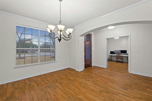 spare room featuring baseboards, arched walkways, wood finished floors, and ornamental molding