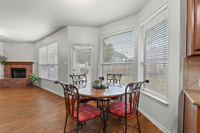 dining space featuring a fireplace, wood finished floors, and baseboards