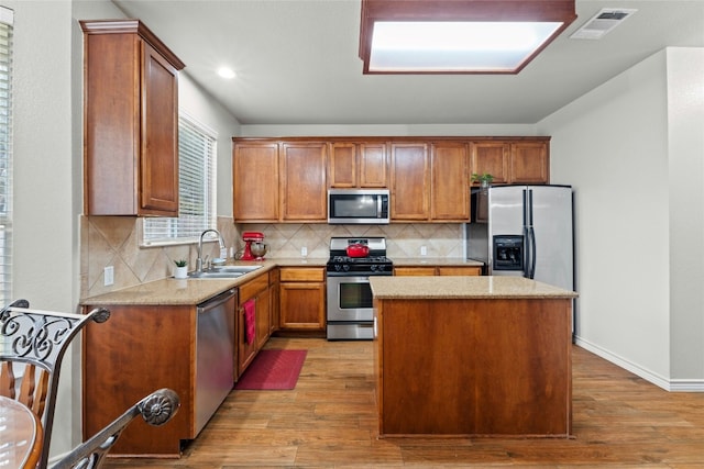 kitchen featuring stainless steel appliances, visible vents, a sink, a kitchen island, and light wood-type flooring