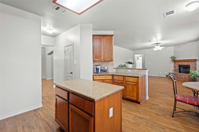 kitchen featuring light wood finished floors, a fireplace, and visible vents