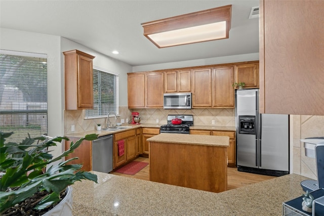 kitchen featuring tasteful backsplash, visible vents, a center island, stainless steel appliances, and a sink