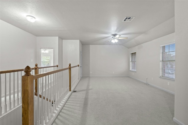 spare room featuring ceiling fan, a textured ceiling, light carpet, visible vents, and baseboards