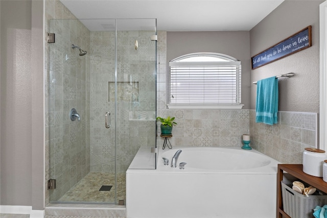 bathroom featuring a garden tub and a shower stall