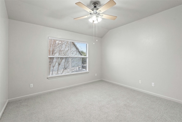 spare room with ceiling fan, baseboards, vaulted ceiling, and light colored carpet