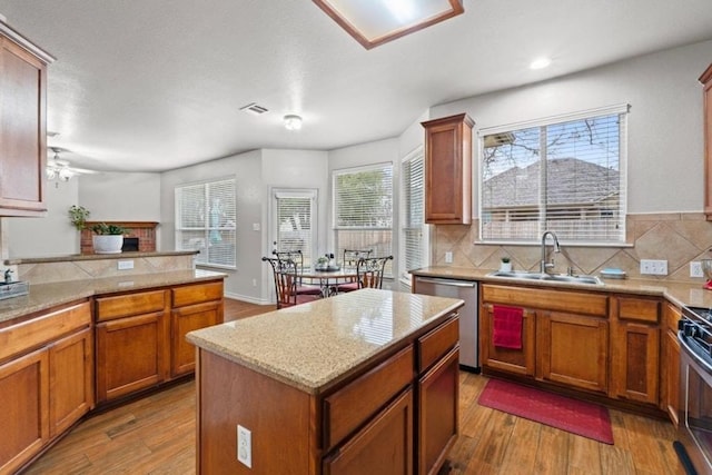 1532 Homewood Cir, Round Rock, TX 78665 - kitchen with a sink, stainless steel dishwasher, wood finished floors, brown cabinetry, and recessed lighting