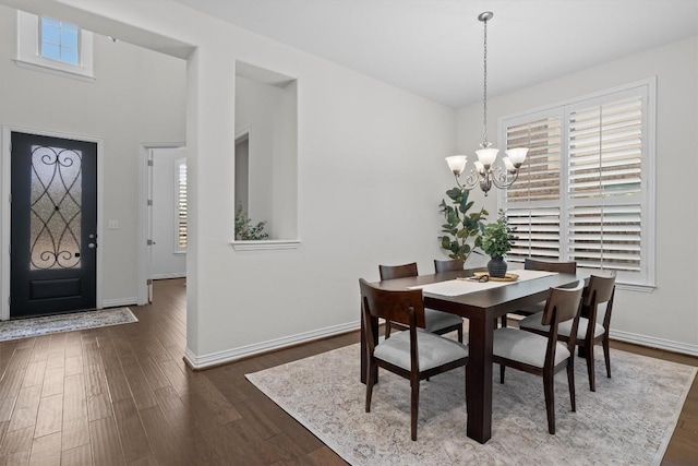 dining space with dark wood-style floors, baseboards, and a notable chandelier