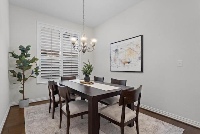 dining area with dark wood-style flooring, baseboards, and an inviting chandelier