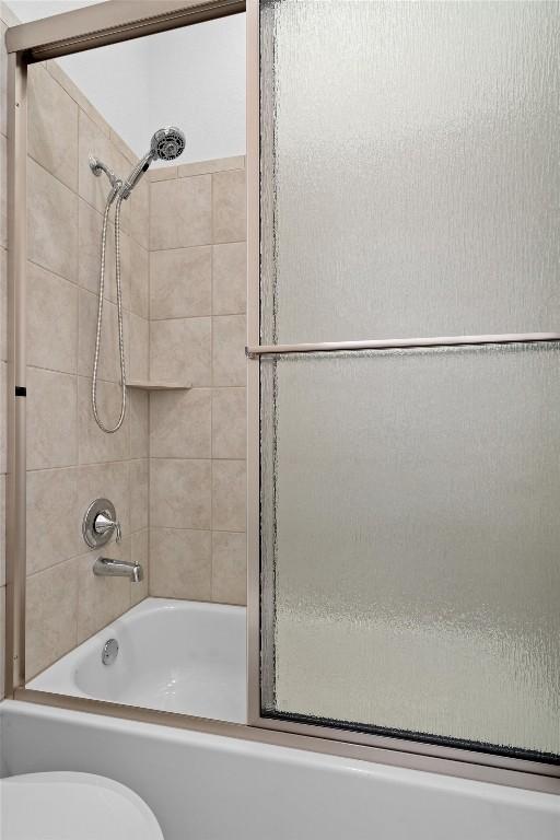 full bathroom featuring combined bath / shower with glass door and toilet